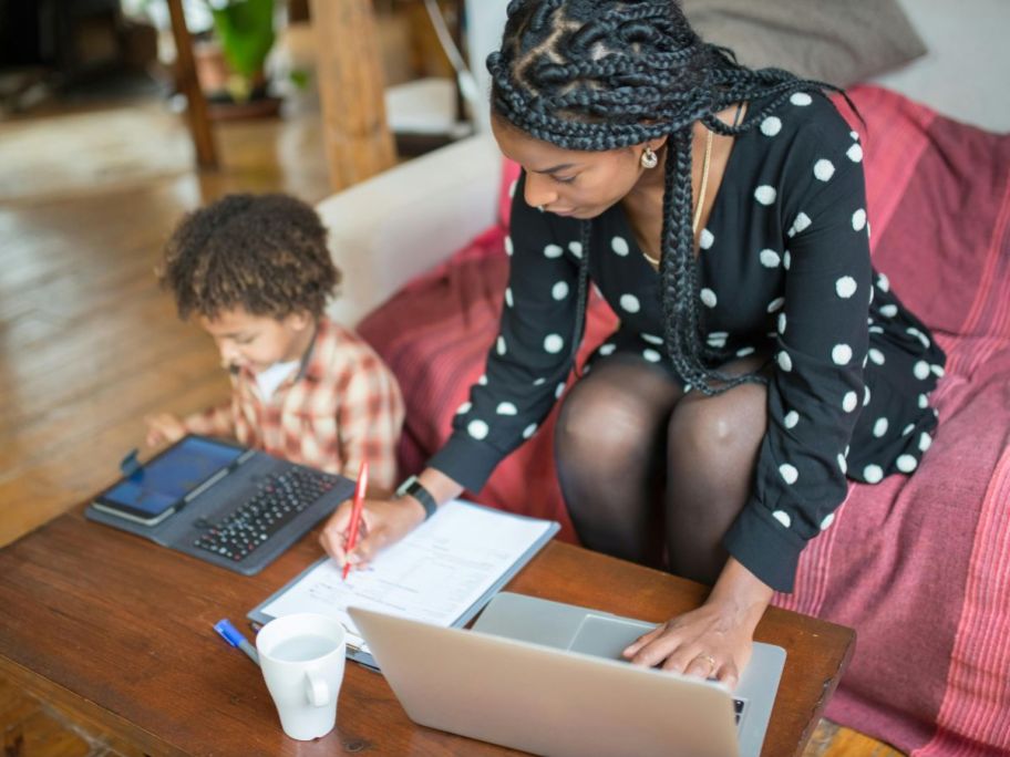 Little boy and woman with a tablet and a laptop at a coffee table in a living room