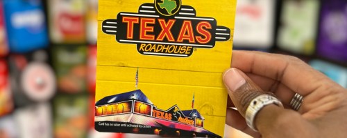 Woman holding up yellow Texas roadhouse gift card