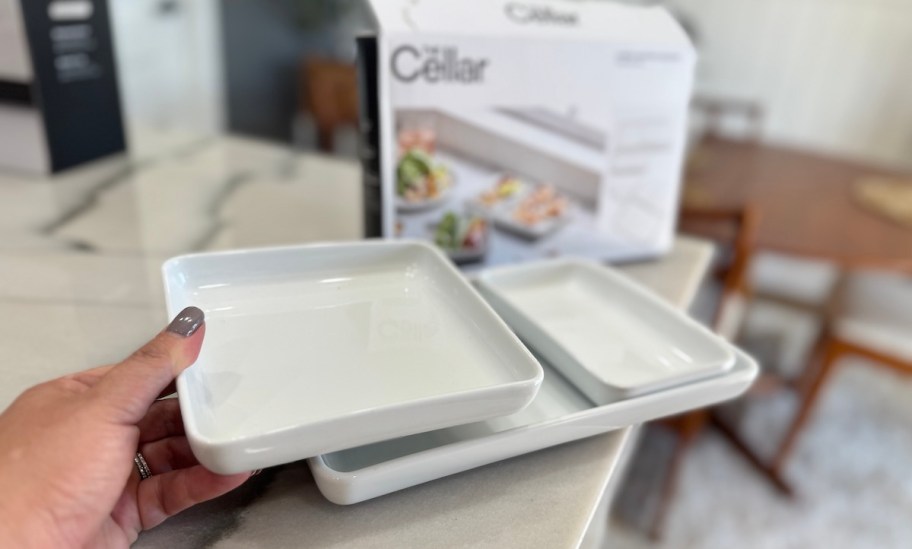 hand holding white nesting platter on kitchen counter