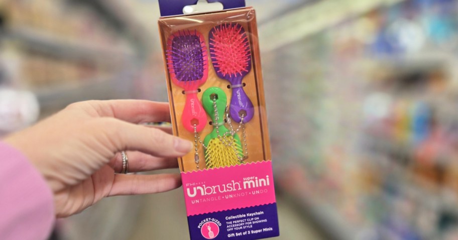 hand holding up a 3-pack of mini hair brushes