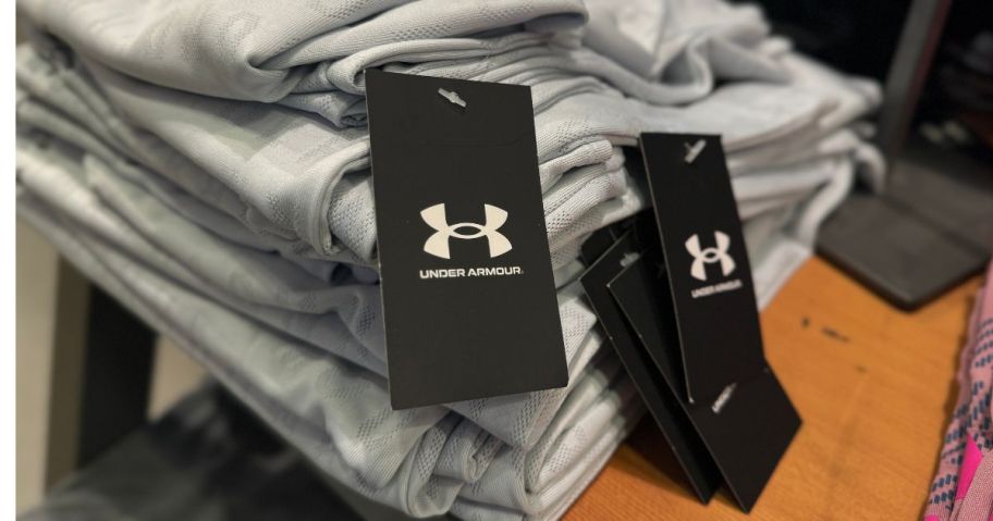 A stack of Under Armour clothing with tags on it
