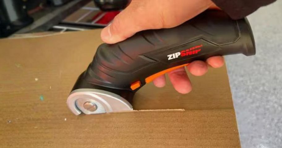 person using WORX 4V ZipSnip Electric Rechargeable Cordless Electric Scissors to cut through cardboard