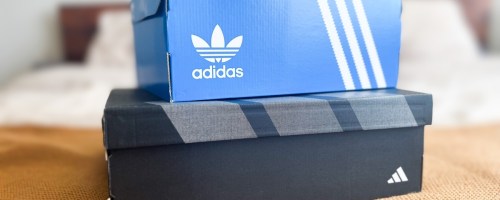 two adidas shoes boxes on the foot of a bed