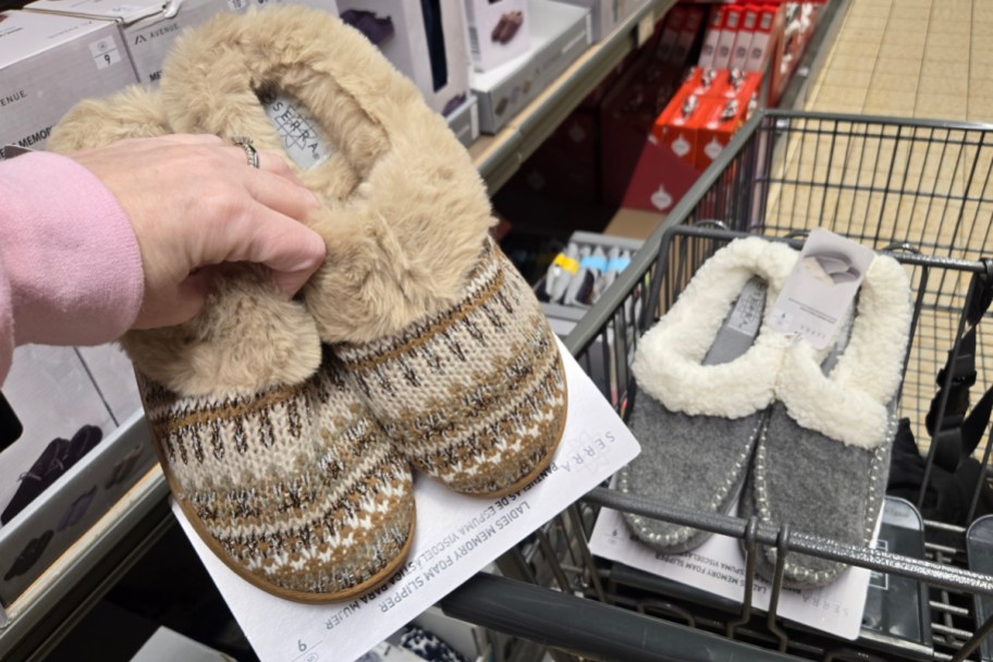 hand holding tan fuzzy slippers next to gray ones in cart