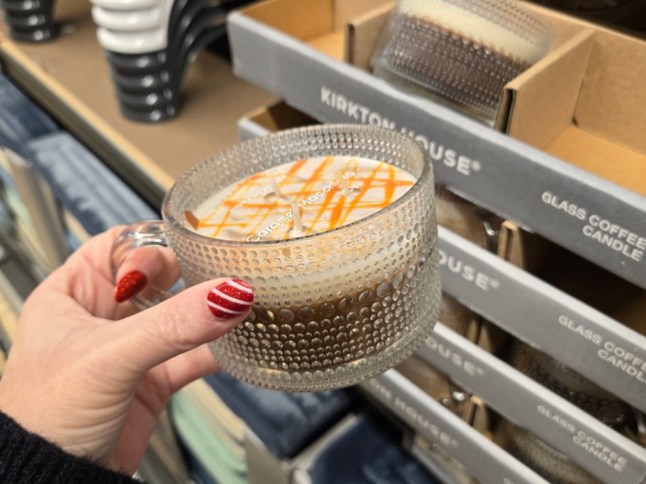 A hand holding up a coffee cup shaped candle at Aldi.