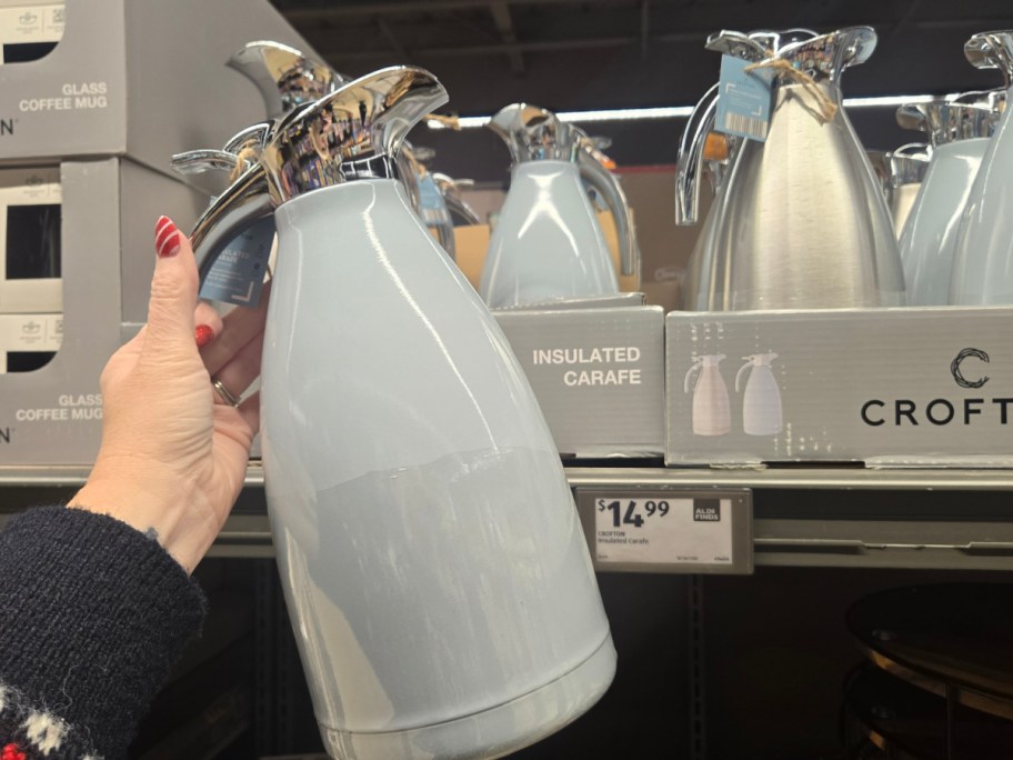 A hand holding up a blue carafe at Aldi.
