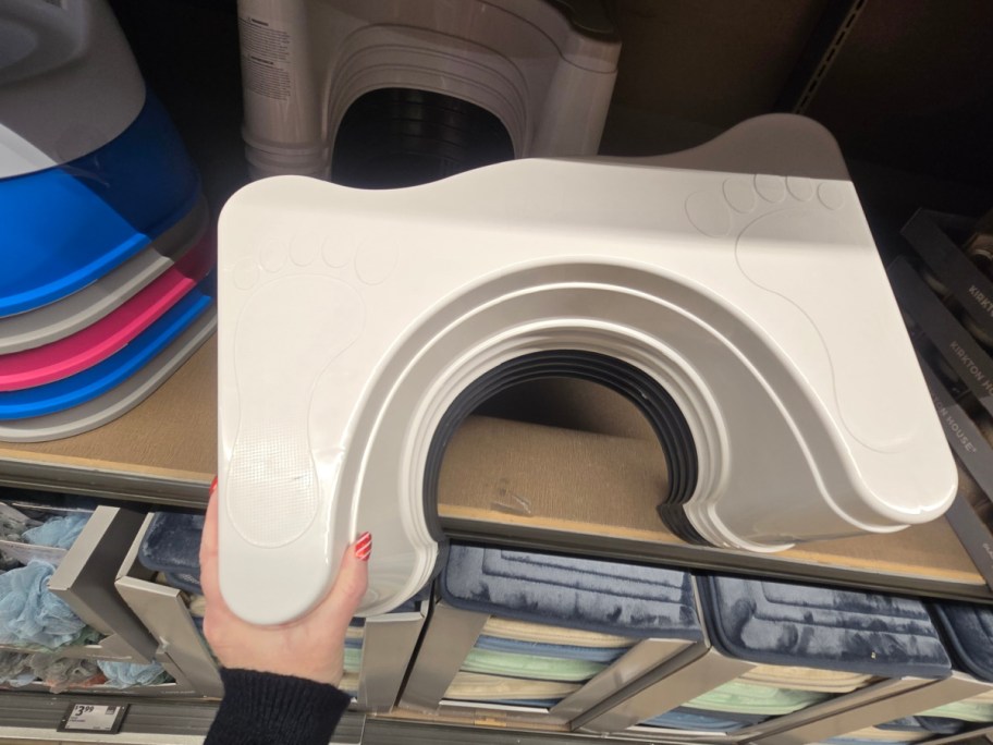 A hand holding up a stack of white stools at Aldi.