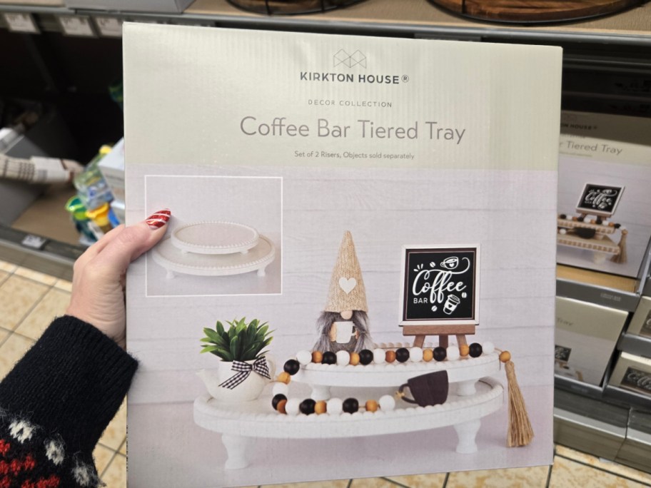 A hand holding up a box of white tiered trays at Aldi.