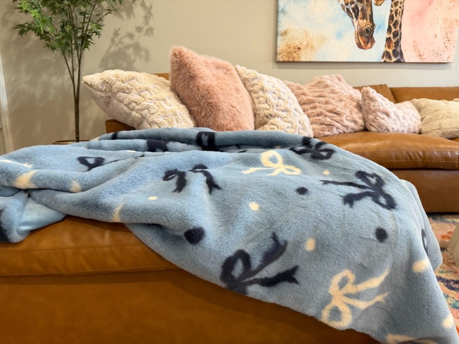 a blanket with blue and white bows on the end of a sofa
