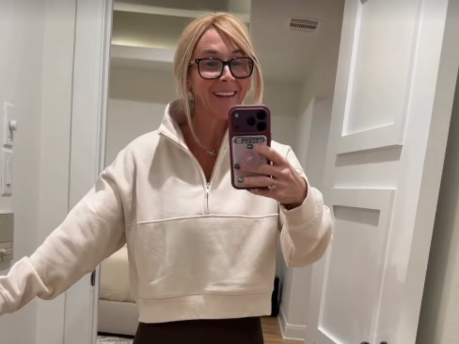 woman in beige quarter zip talking selfie