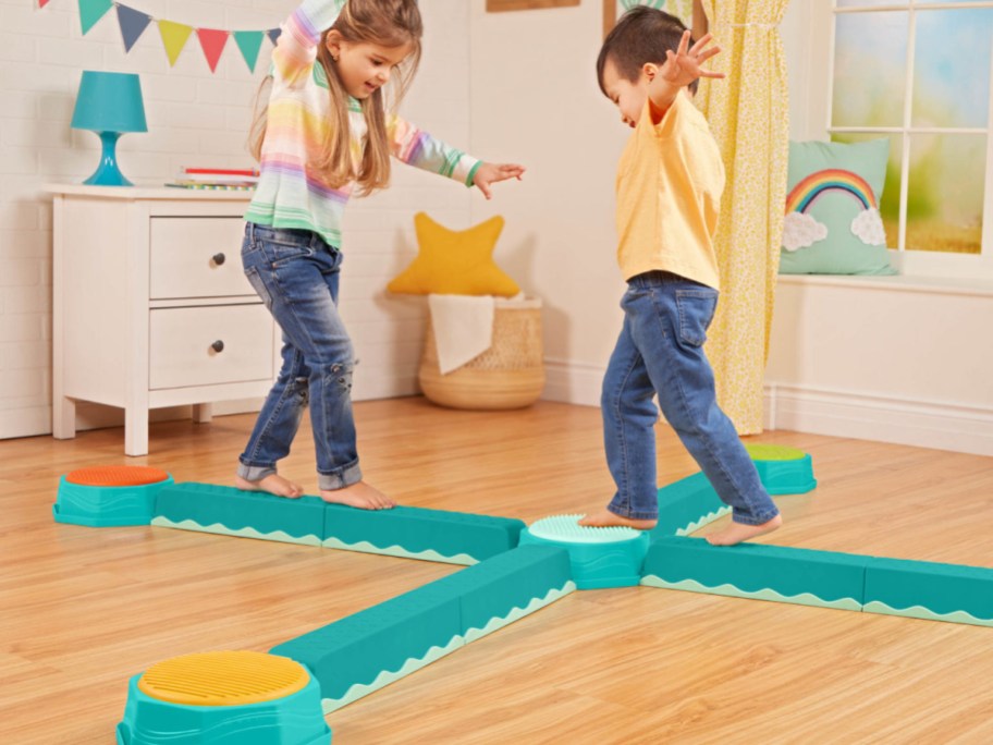 Two kids playing on a balance beam toy.