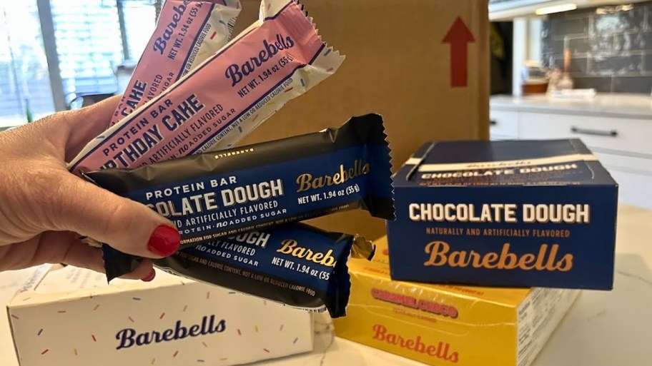 a womans hand holding barebells protein bars