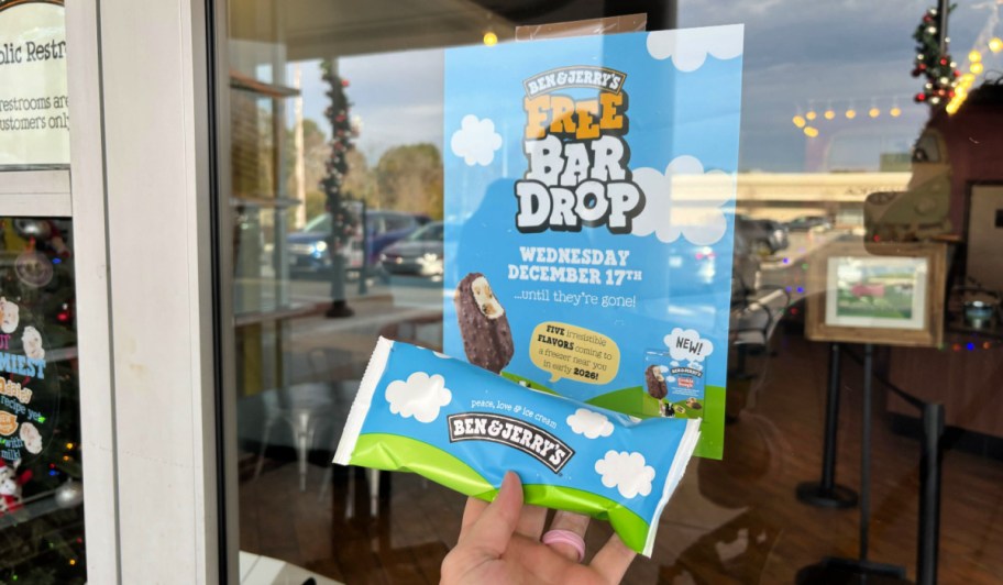 woman holding an ice cream bar in front of a ben & jerry's bar drop sign