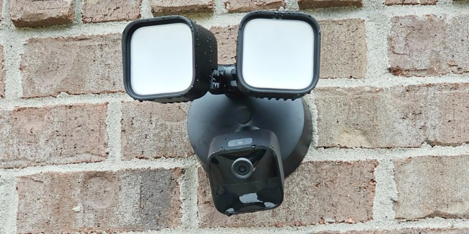black floodight with camera hanging on wall 