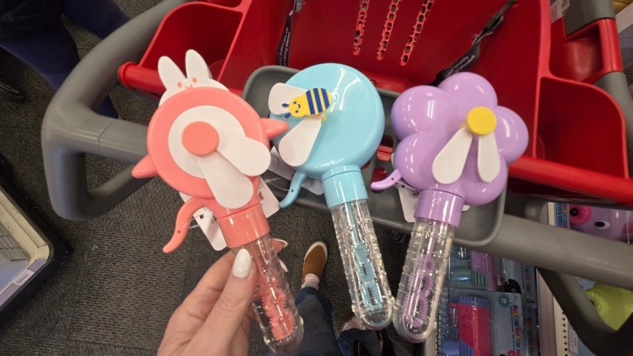 womans hand holding a bubble wand next to two other bubble wands