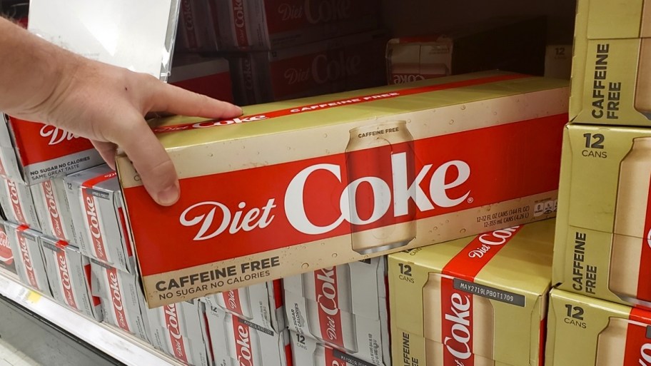 a hand reaching for a caffeine free 12 pack of diet coke
