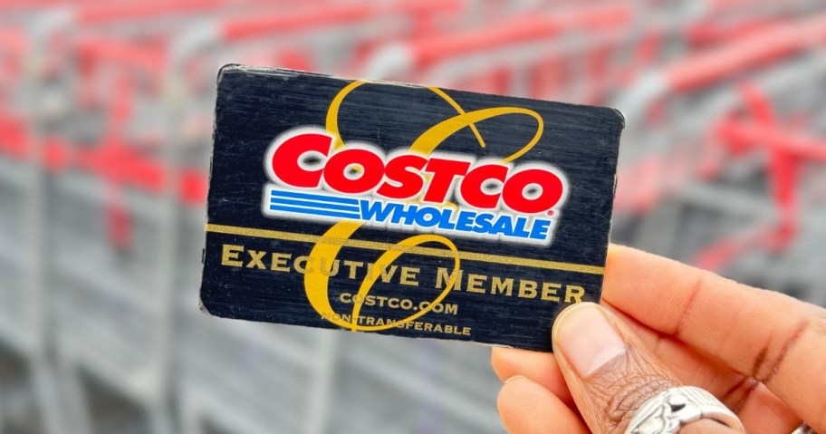 hand holding a Costco membership card in front of shopping carts