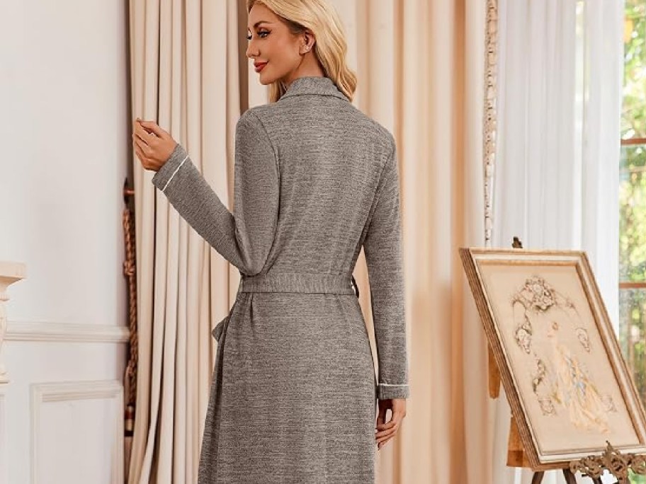 woman wearing brown bathrobe standing by curtain
