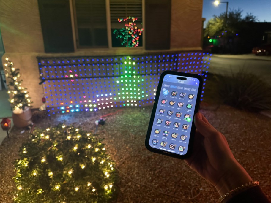 hand holding phone with app to control christmas lights in background