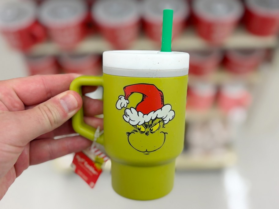 hand holding green grinch tumbler