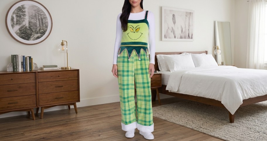 woman wearing a grinch jumpsuit standing in a bedroom