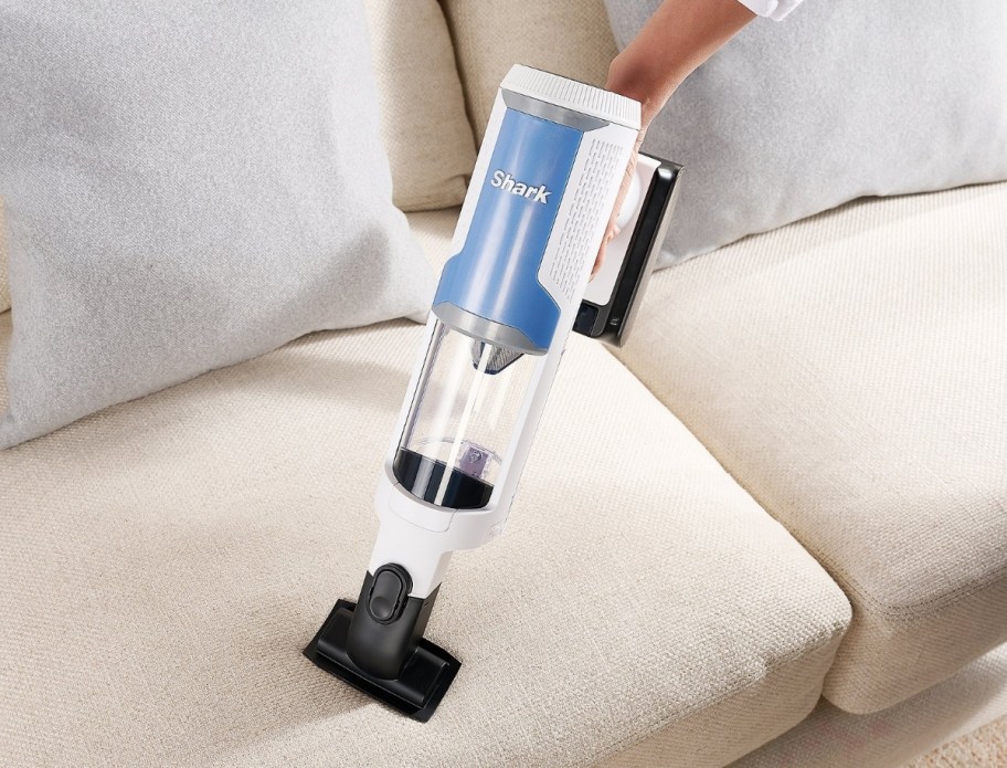 a woman vacuuming a sofa with a hand vac
