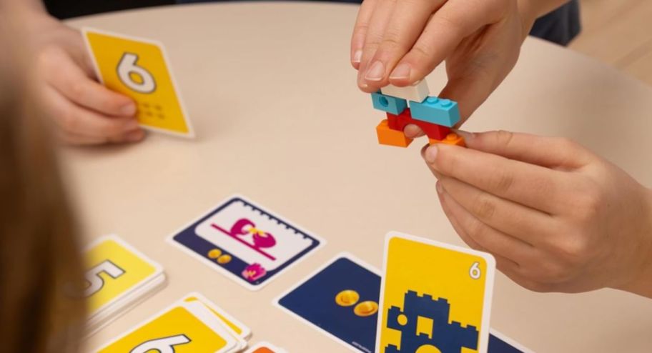 hand holding LEGO pieces with items on top of the table