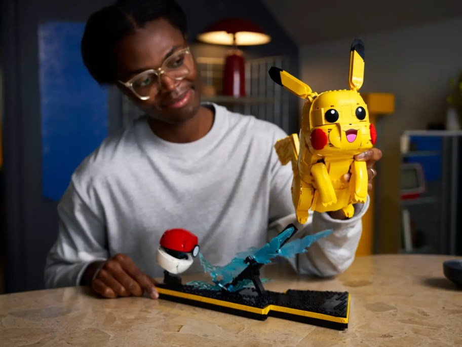 A kid holding up a LEGO Pokemon Pickachu set complete.