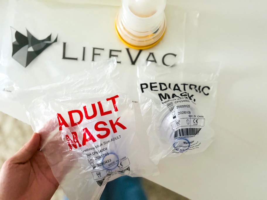 hand holding adult mask with lifevac in background