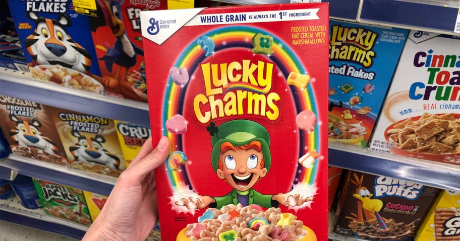 person holding box of lucky charms cereal