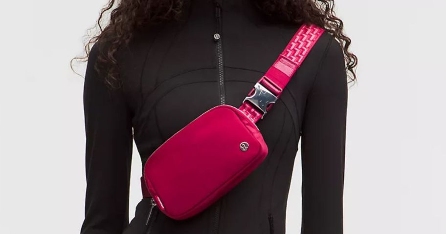 A person wearing black with a pink belt bag across their chest