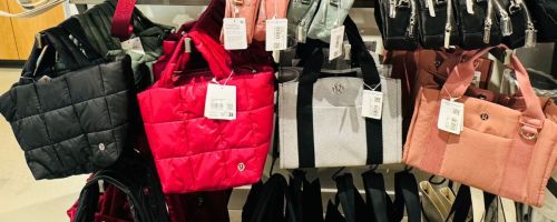 lots of lululemon bags at the store on a rack