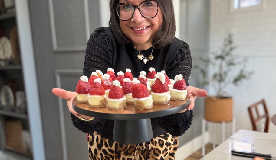 woman holding up cake stand with strawberry desserts 