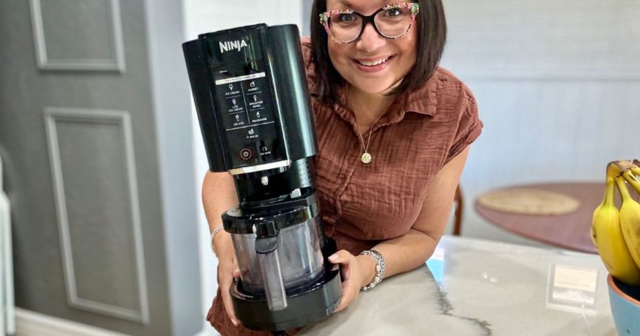 woman holding ninja creami in her kitchen 