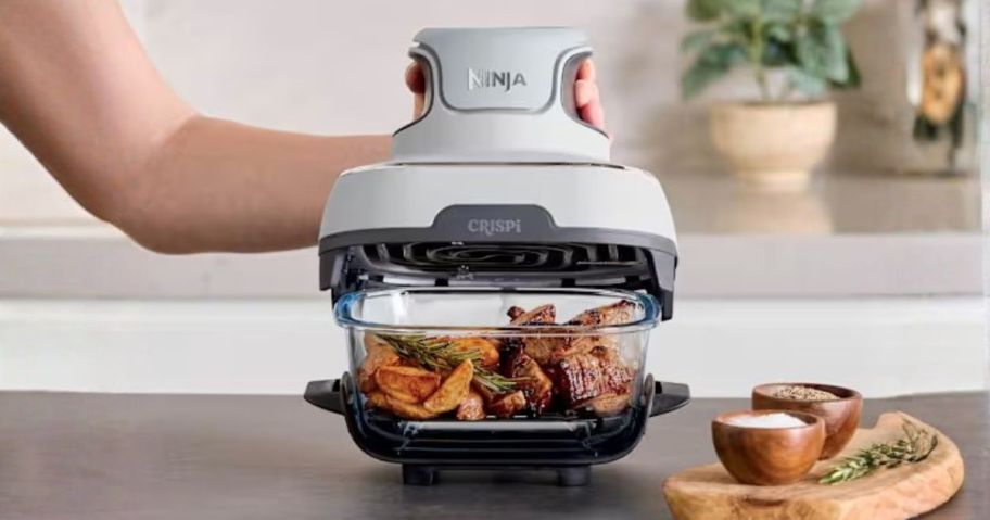 person holding Ninja Crispi 3-in-1 Glass Air Fryer on counter