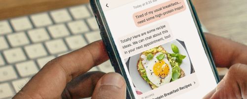 holding a phone showing a nutrition app in front of a keyboard