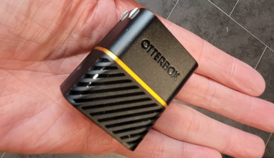 a hand holding an otterbox charger