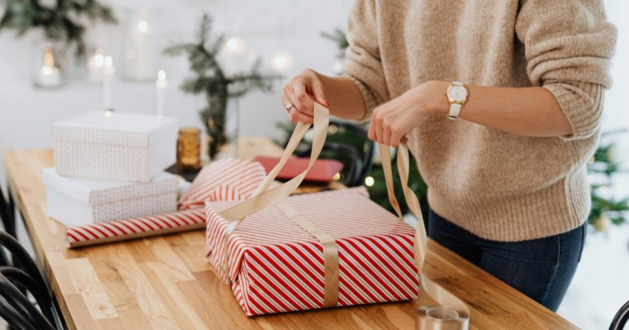 person wrapping christmas gifts on wrapping table
