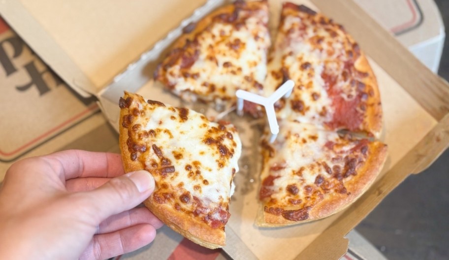 a hand grabbing a slice of pizza