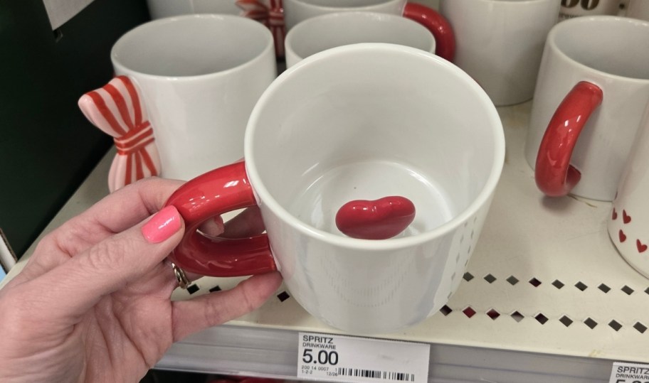 womans hand holding a red and white peekaboo heart mug