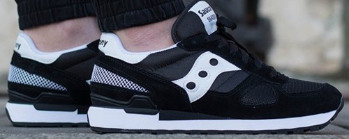 person wearing black and white saucony shoes
