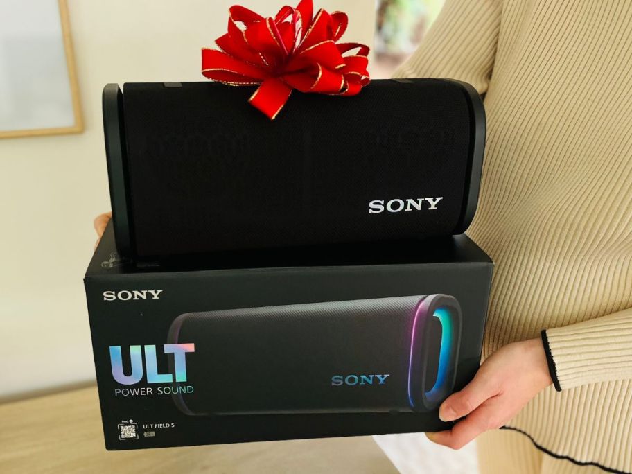 woman holding Sony ULT FIELD 5 Wireless Portable Speaker box with bow on it