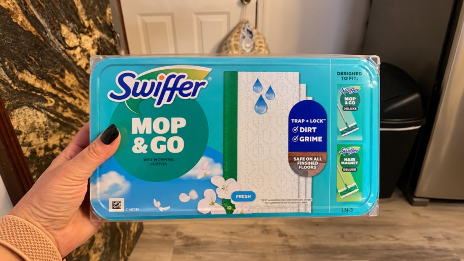 womans hand holding a package of wet mopping cloths