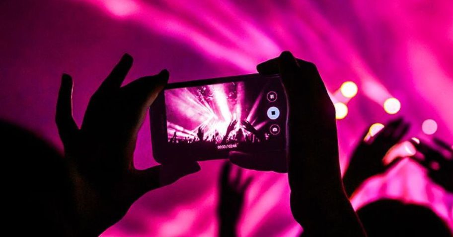 person holding up smart phone at concert