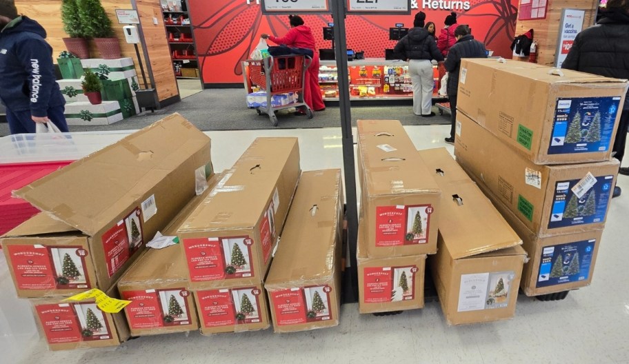 artificial christmas trees stacked on a store aisle