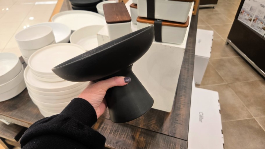hand holding up a black footed bowl in a store