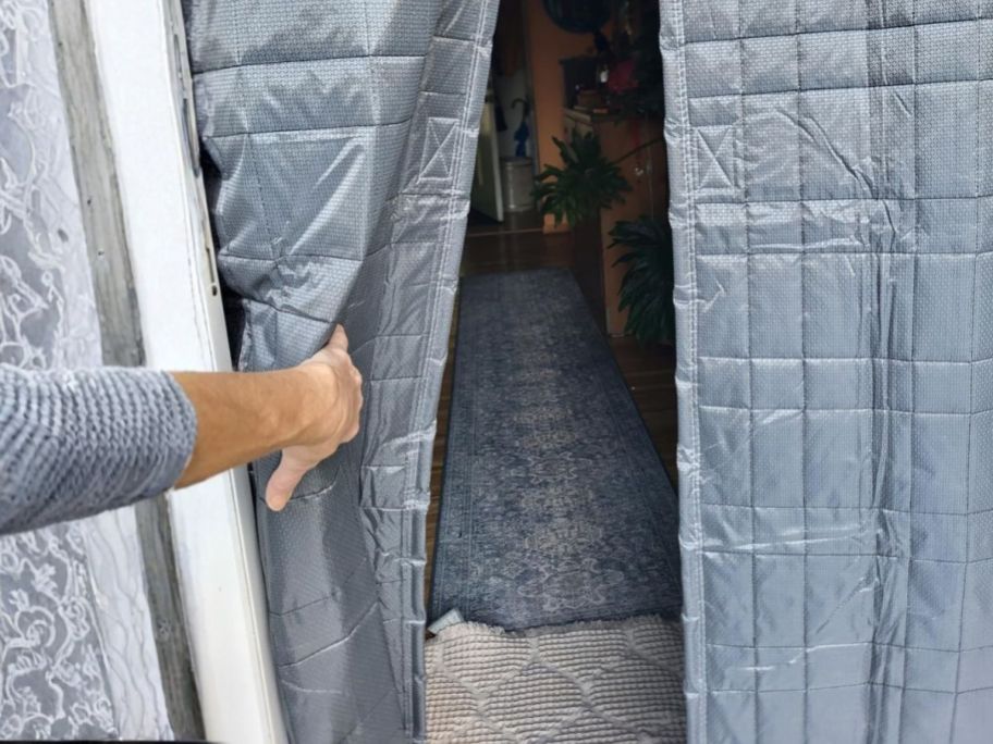 person holding open thermal door curtain