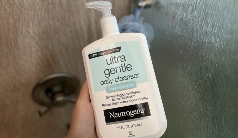 a womans hand holding a bottle of neutrogena facial cleanser