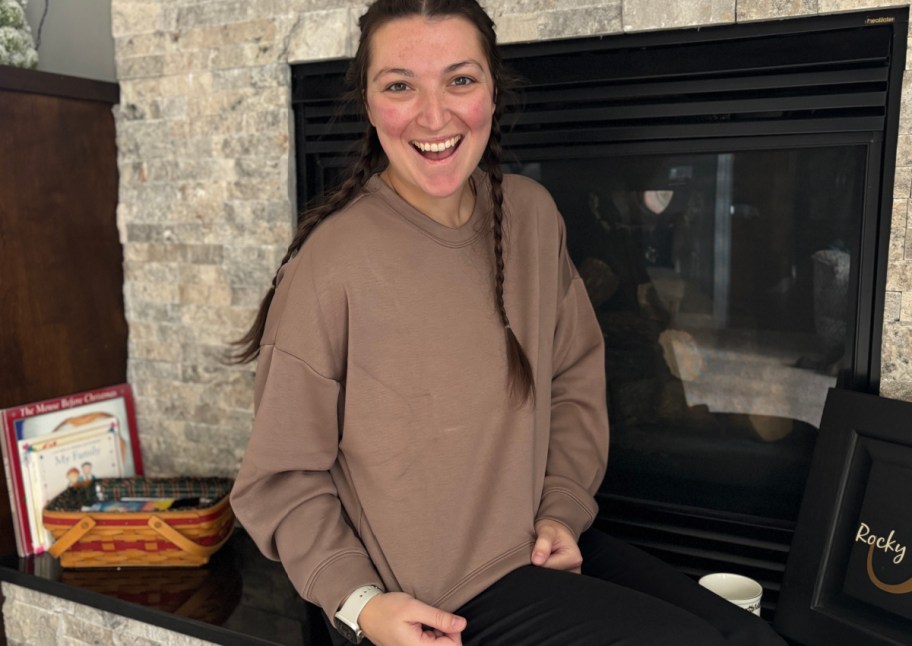 woman sitting near fireplace in mocha sweatshirt