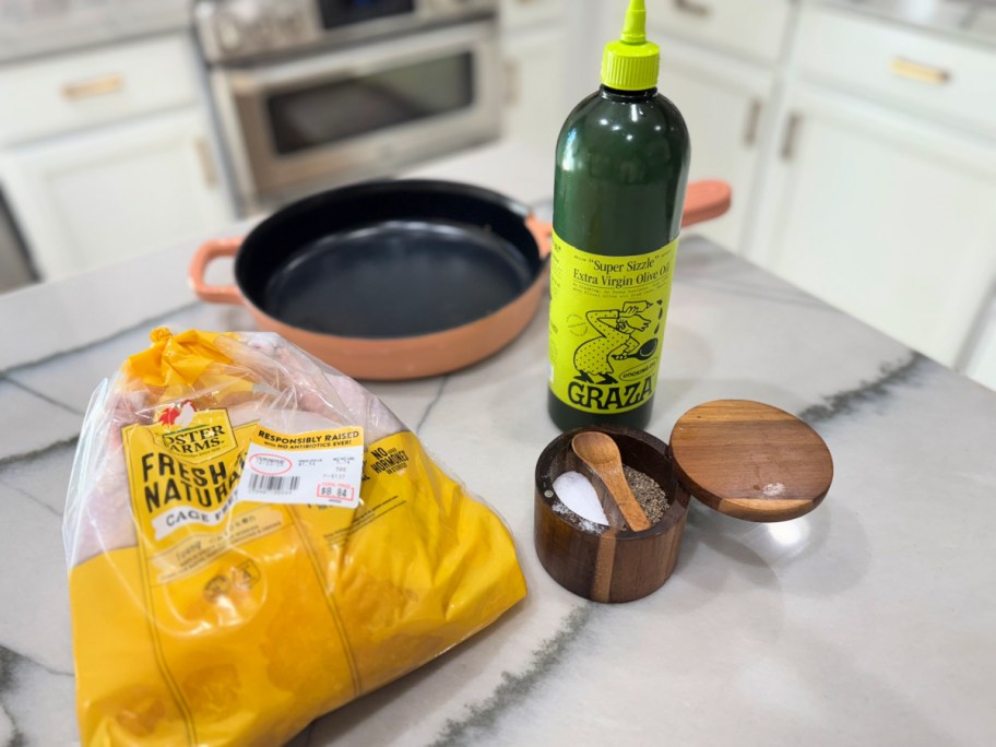 whole chicken on the counter with skillet olive oil and salt and pepper